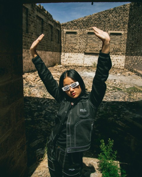 a woman in a black jacket is holding her hands up