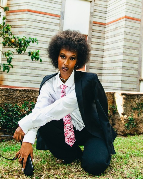 a woman in a suit and tie kneeling on the grass