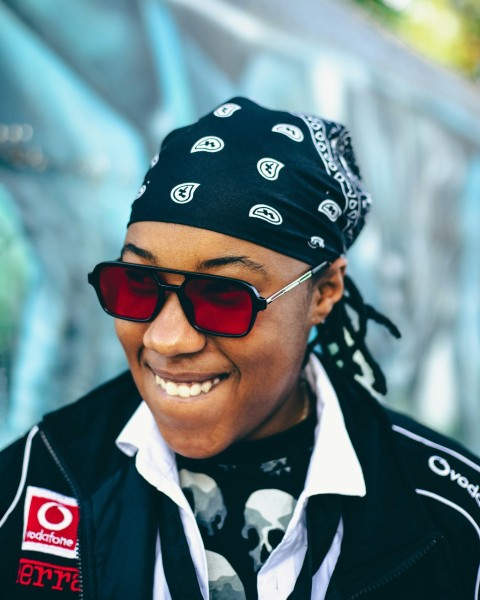 a woman wearing sunglasses and a bandana smiles