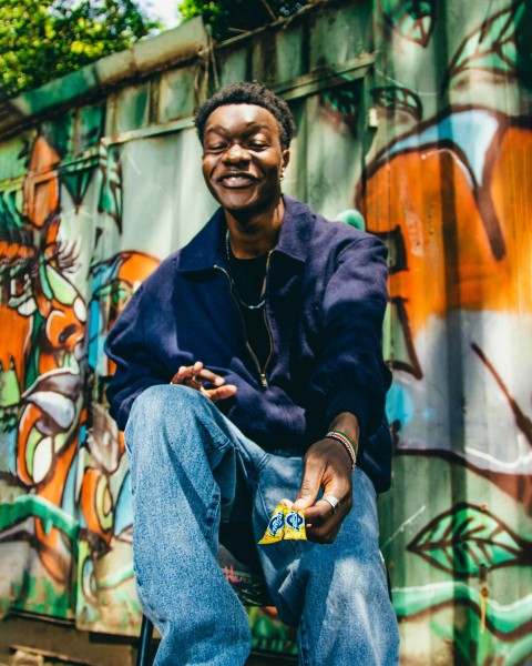 a man sitting in front of a graffiti covered wall