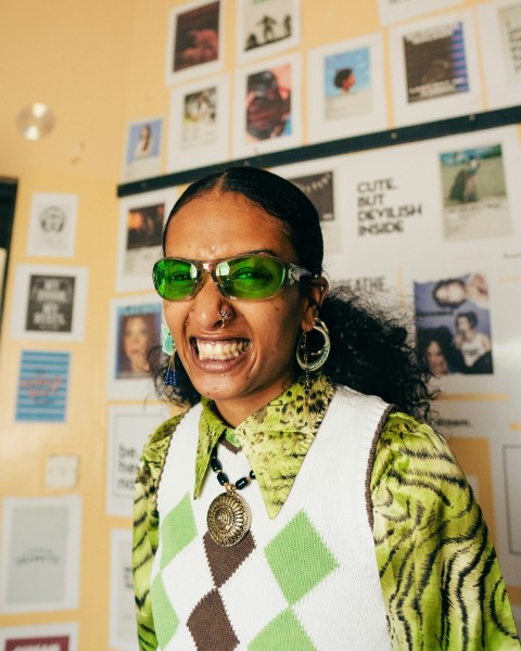 a woman wearing green sunglasses and a sweater