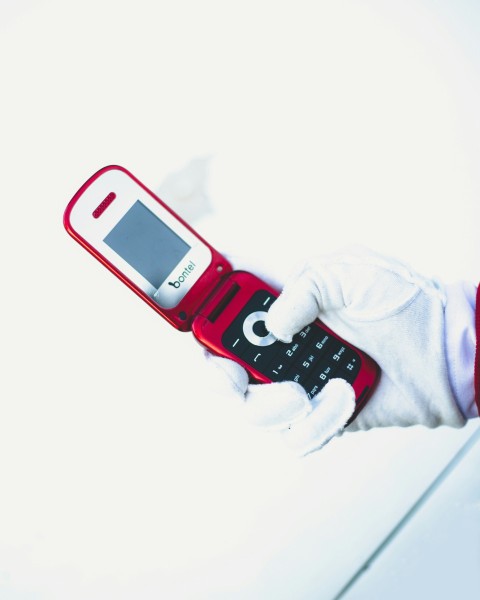 a person in white gloves holding a red cell phone