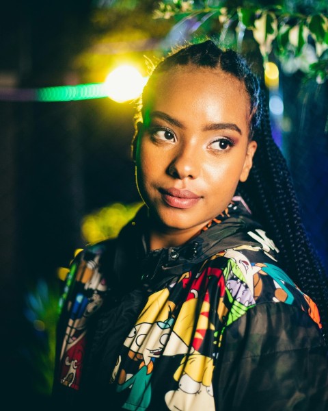 a woman with braids standing in front of a tree