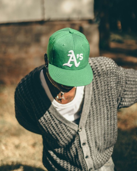 a man wearing a green hat with a white as on it