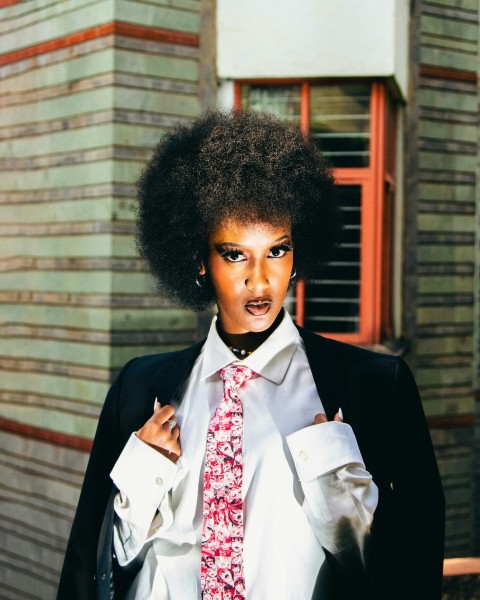 a woman in a suit and tie with an afro