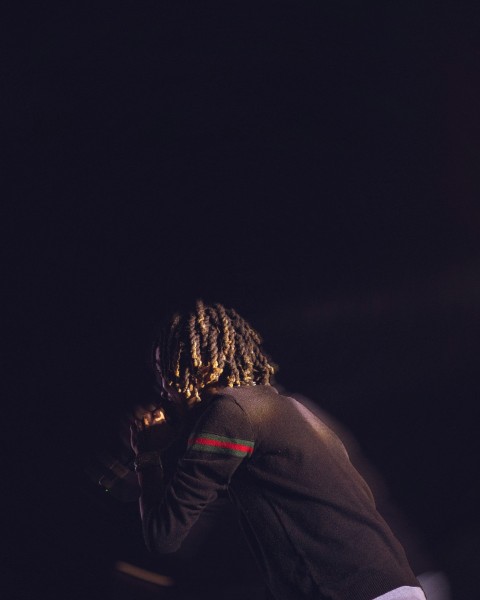 a man with dreadlocks standing in the dark Om