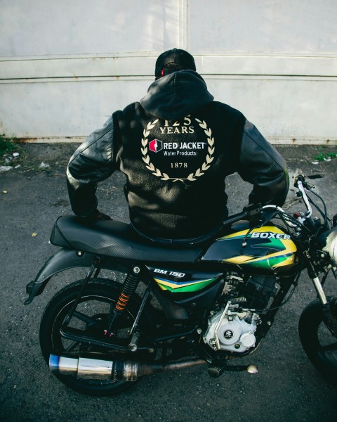 a man sitting on a motorcycle wearing a hoodie