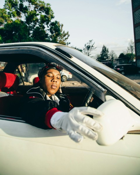 a woman sitting in a car with gloves on c5ojciH6