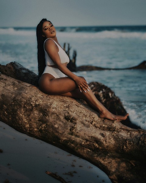 a woman is sitting on a log by the water