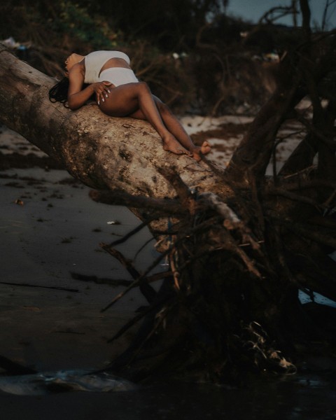 a woman laying on top of a tree branch