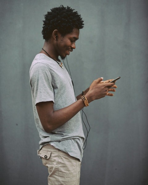 man in white crew neck t shirt holding smartphone