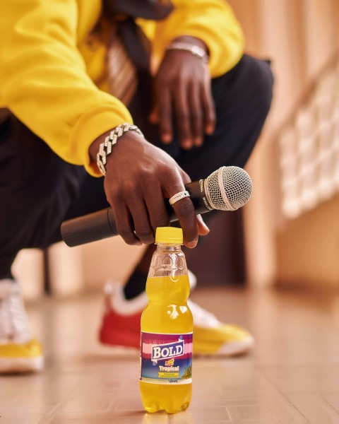 a man holding a microphone and a bottle of soda