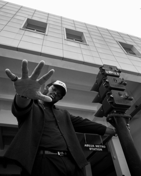 a man in a suit and hat holding his hand up