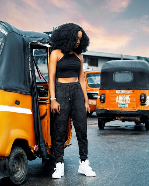 woman in black tank top and gray pants standing beside yellow van during daytime