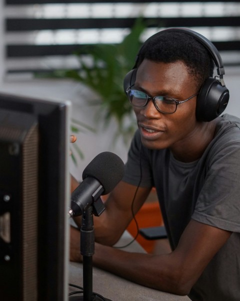 a man wearing headphones sitting in front of a computer cPqvyw