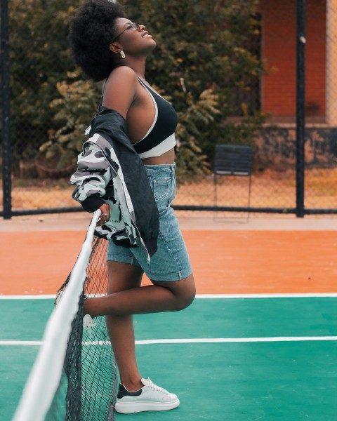 woman in black and white stripe shirt and blue denim shorts standing on basketball court UAo