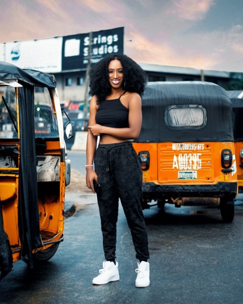 woman in black tank top and black pants standing beside yellow bus during daytime