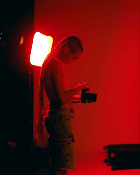 a woman standing in front of a red light holding a camera