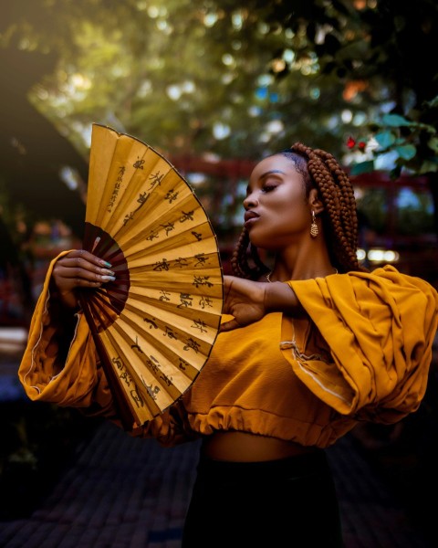 a woman in a yellow top holding a yellow fan kSlQrz2e