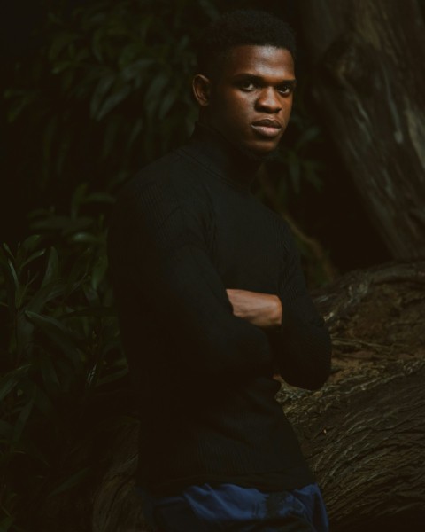 a man sitting in front of a tree with his arms crossed