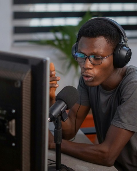 a man wearing headphones and a microphone in front of a computer