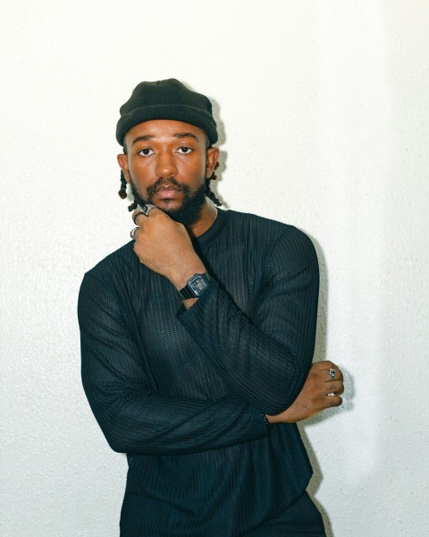 a man in a black shirt and hat posing for a picture SMZUTDxF