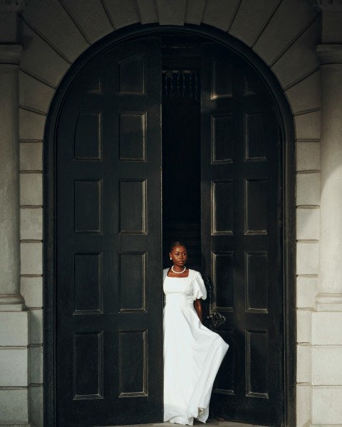 a woman in a white dress standing in a doorway wO1yoM