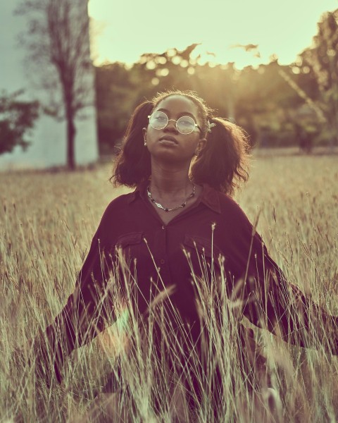 woman in black jacket standing on green grass field during sunset