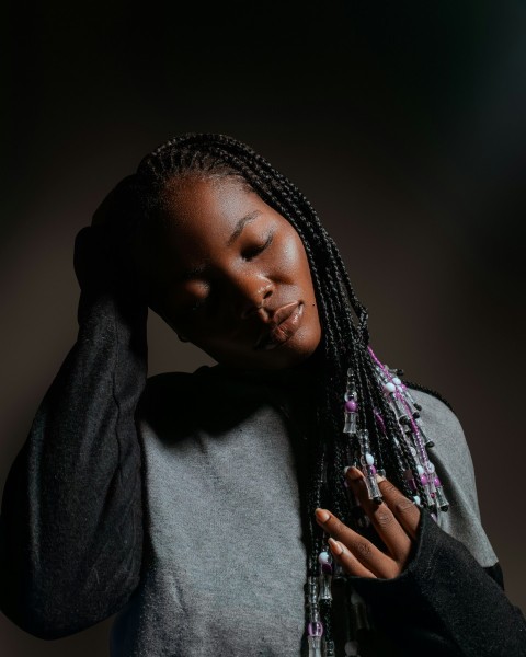 a woman with dreadlocks holding her head in her hands