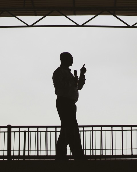 silhouette of man standing near fence during daytime