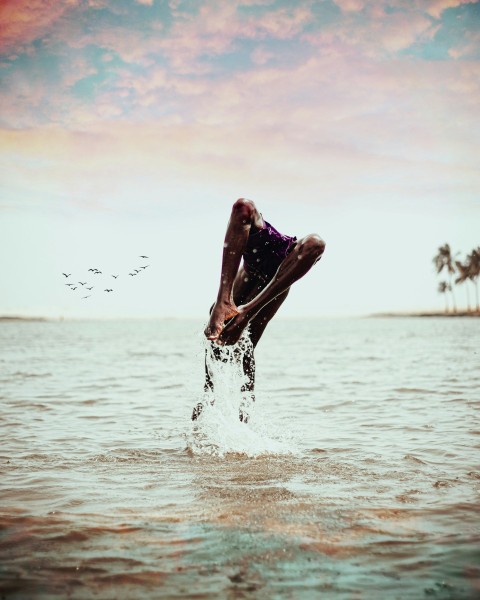 a man jumping into the ocean from the water u1md25Zj