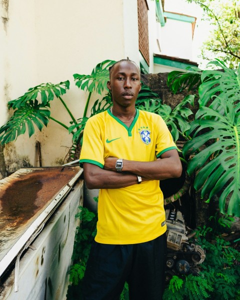 a man in a yellow shirt standing in front of a plant