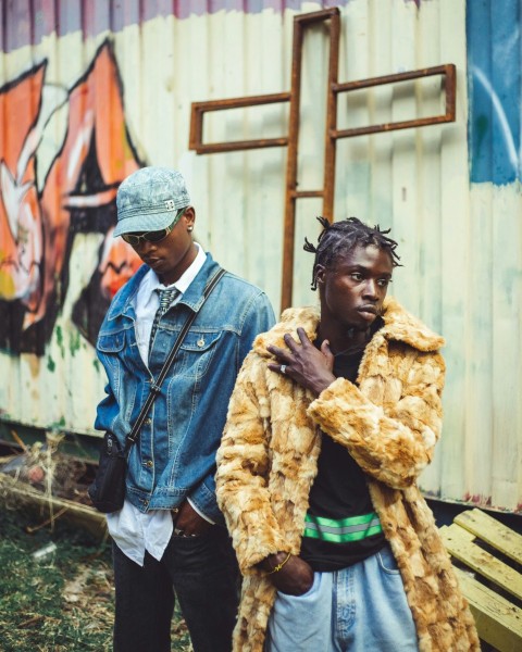 two men standing next to each other in front of a building