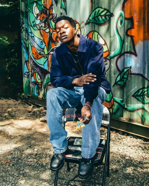 a man sitting on a chair in front of a graffiti covered wall