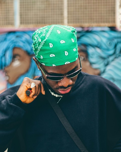 a man wearing a green bandana while talking on a cell phone