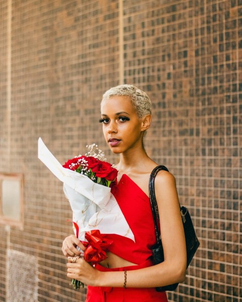 a woman in a red dress holding a bouquet of flowers B k