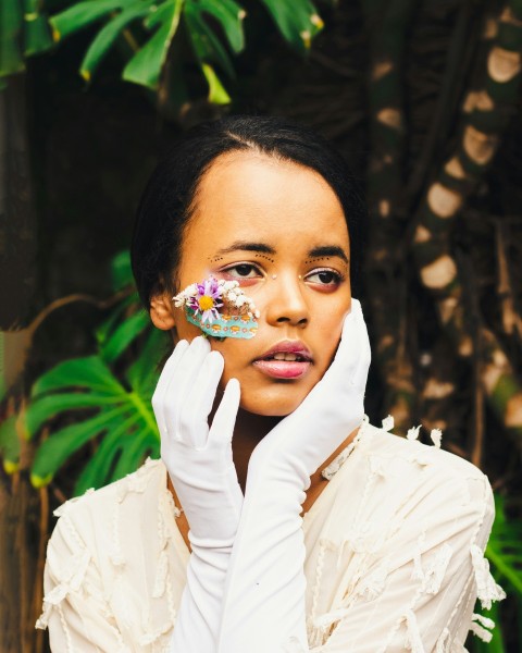 a woman in white gloves holding a doughnut to her face