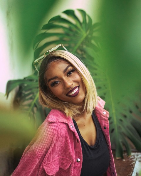 a woman in a pink jacket and sunglasses posing for a picture