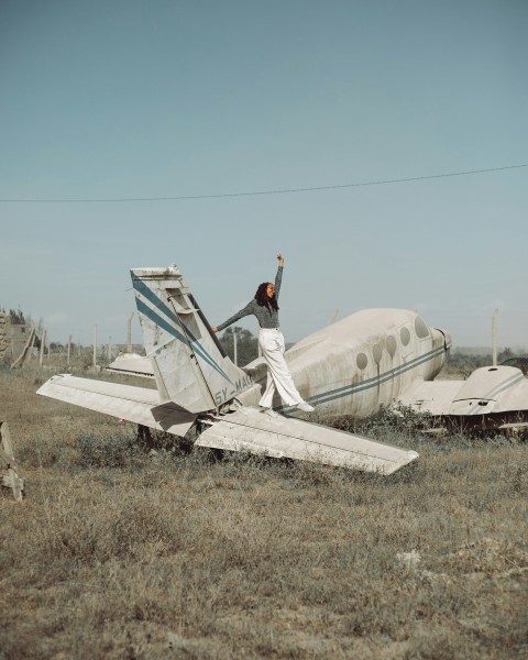 a woman standing on top of a broken plane in a field pWKBD2