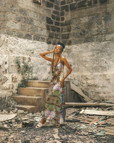 a person in a dress standing in front of a stone building