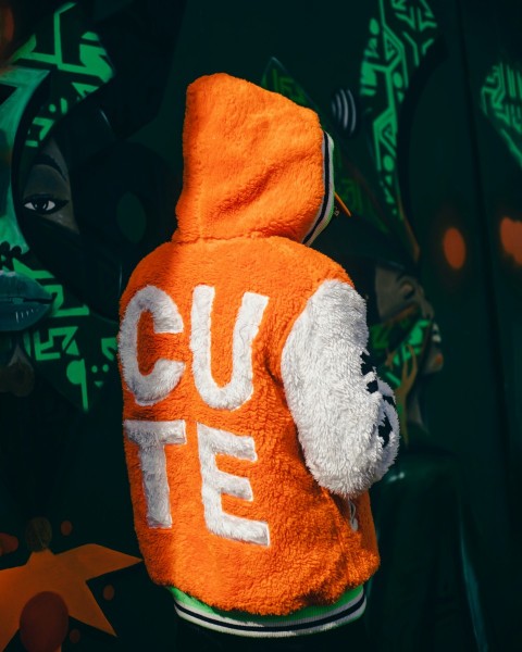 a teddy bear wearing an orange hoodie with the word cut out on it