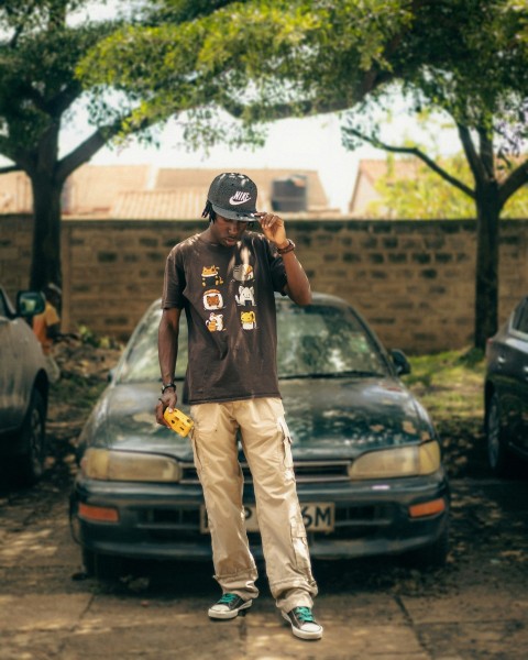 a man standing in front of a car talking on a cell phone