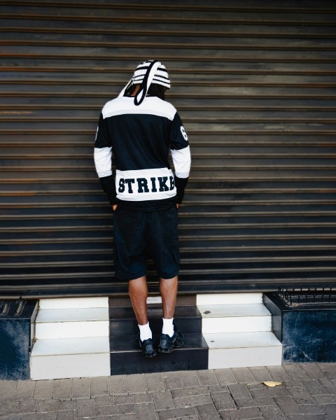 a man standing in front of a garage door wearing a black and white hoodie