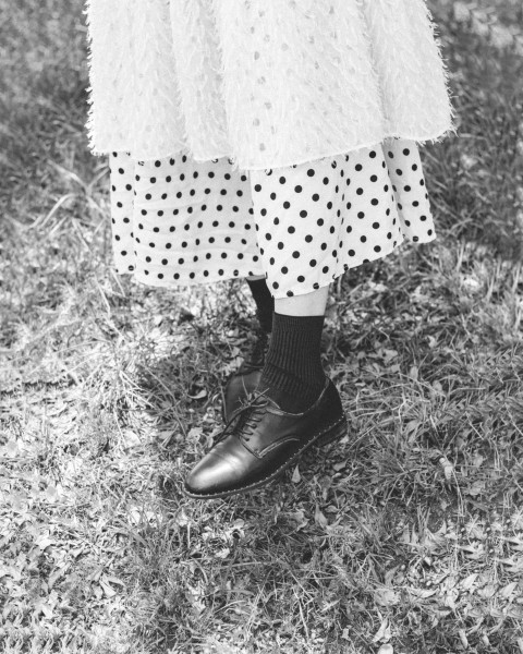 a black and white photo of a person wearing a dress and shoes