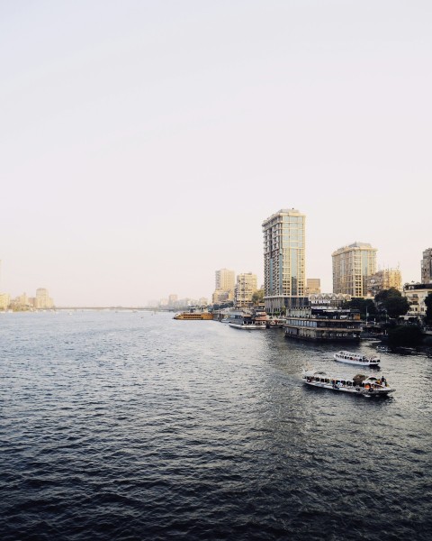 a group of boats in a body of water with buildings in the background