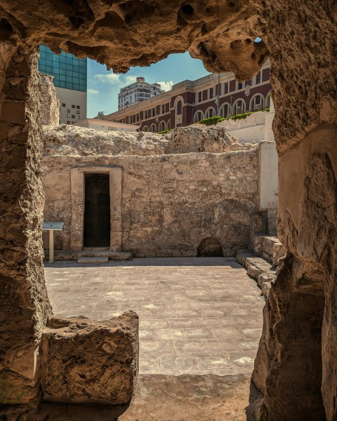 a view of a building through a hole in a stone wall