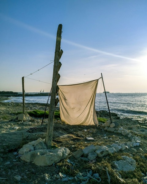 a clothes line on a rocky beach next to a body of water