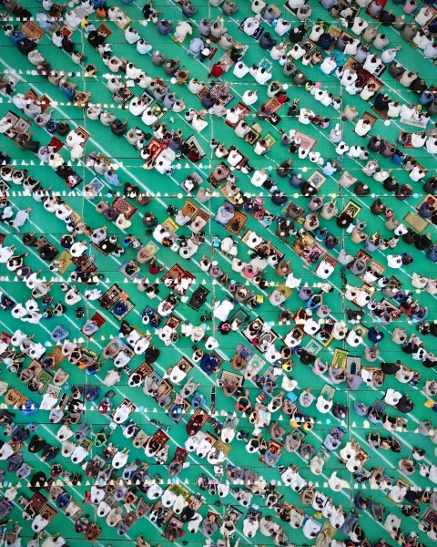 a large group of people standing around a green field