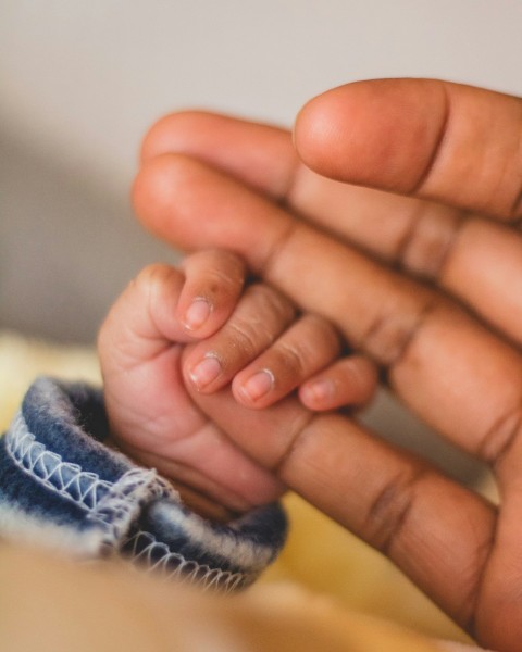 childs hand gripping persons pinkie finger