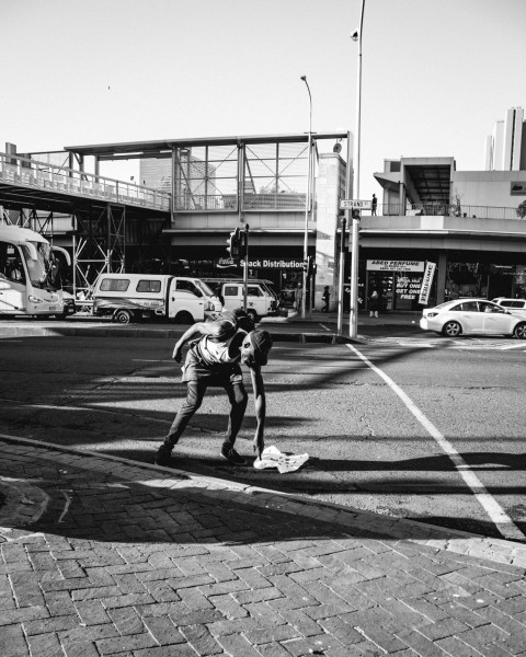 grayscale photo of man in t shirt and shorts walking on pedestrian lane